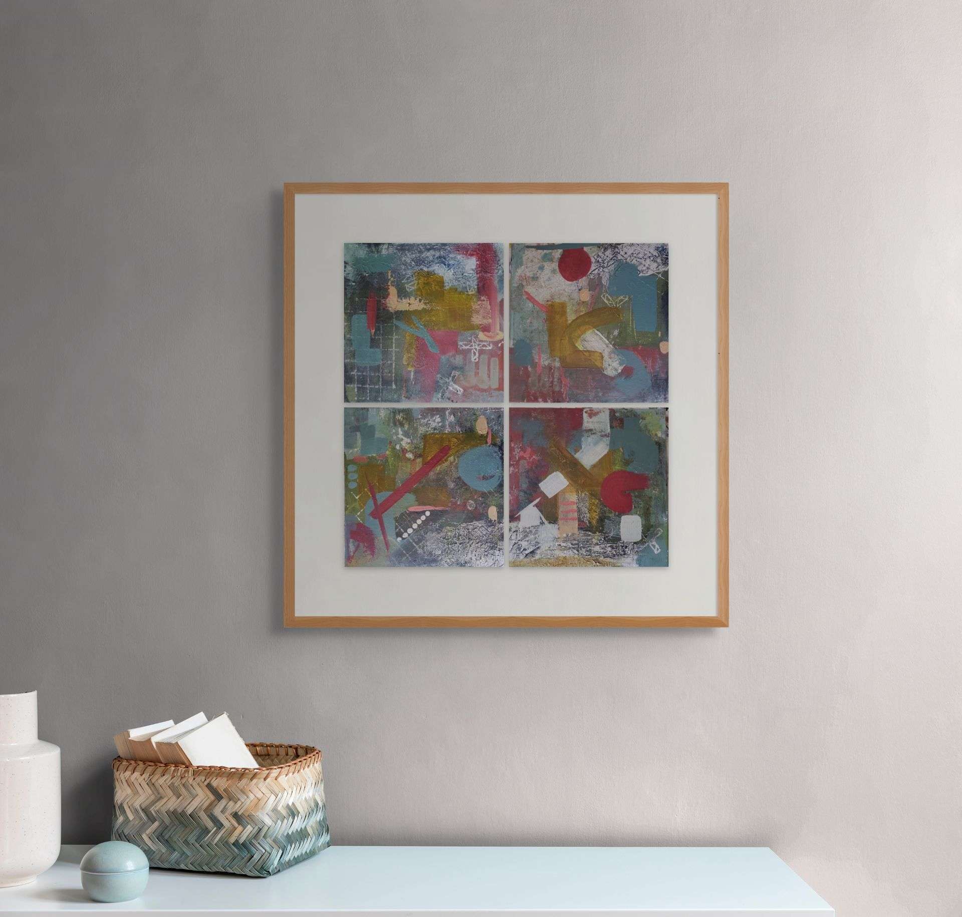 Abstract tetraptych of four small canvases in shades of teal and deep red, framed as a single artwork and displayed on a neutral wall in a hallway setting